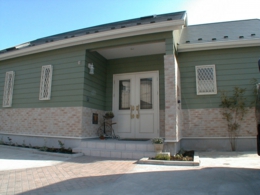 グリーンのラップサイディングの平屋